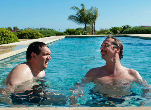 Geschäftsmeeting im Pool: Lorenz (Charly Hübner, l.) und Alexander (Michael Maertens, r.) genießen den neuen Luxus auf Mallorca. Bild: Sender / Max Kohr