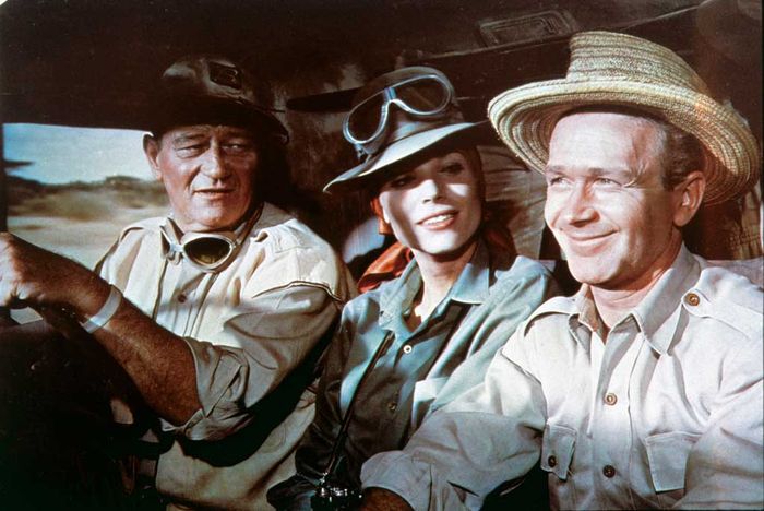 Sean Mercer (John Wayne) und Pockets (Red Buttons, r.) sind hartgesottene Großwildjäger einer Fangstation in Tansania. Eines Tages stößt die junge Fotografin Anna Maria "Dallas" D'Allessandro (Elsa Martinelli, M.) zu ihrem Team ... Bild: Sender / Russell Harlan